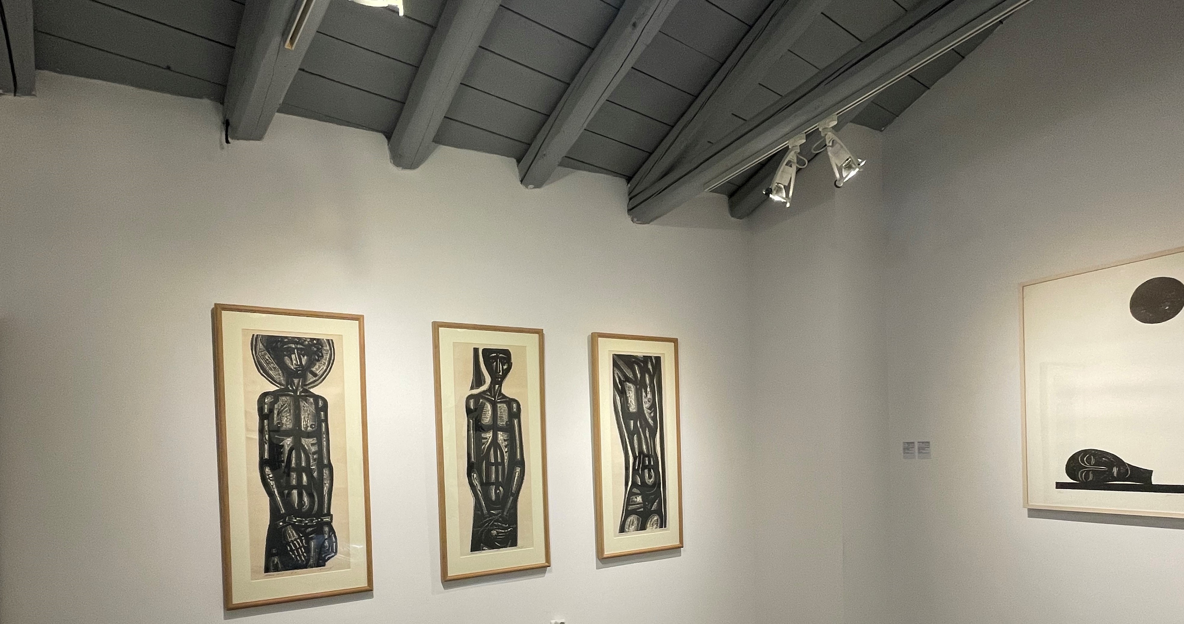 Τα έργα Σκλάβος 1, Σκλάβος 2 και Σκλάβος 3 κρέμονται σε λευκό τοίχο. Στο πλάι άλλο έργο. Τα έργα στον χώρο της έκθεσης