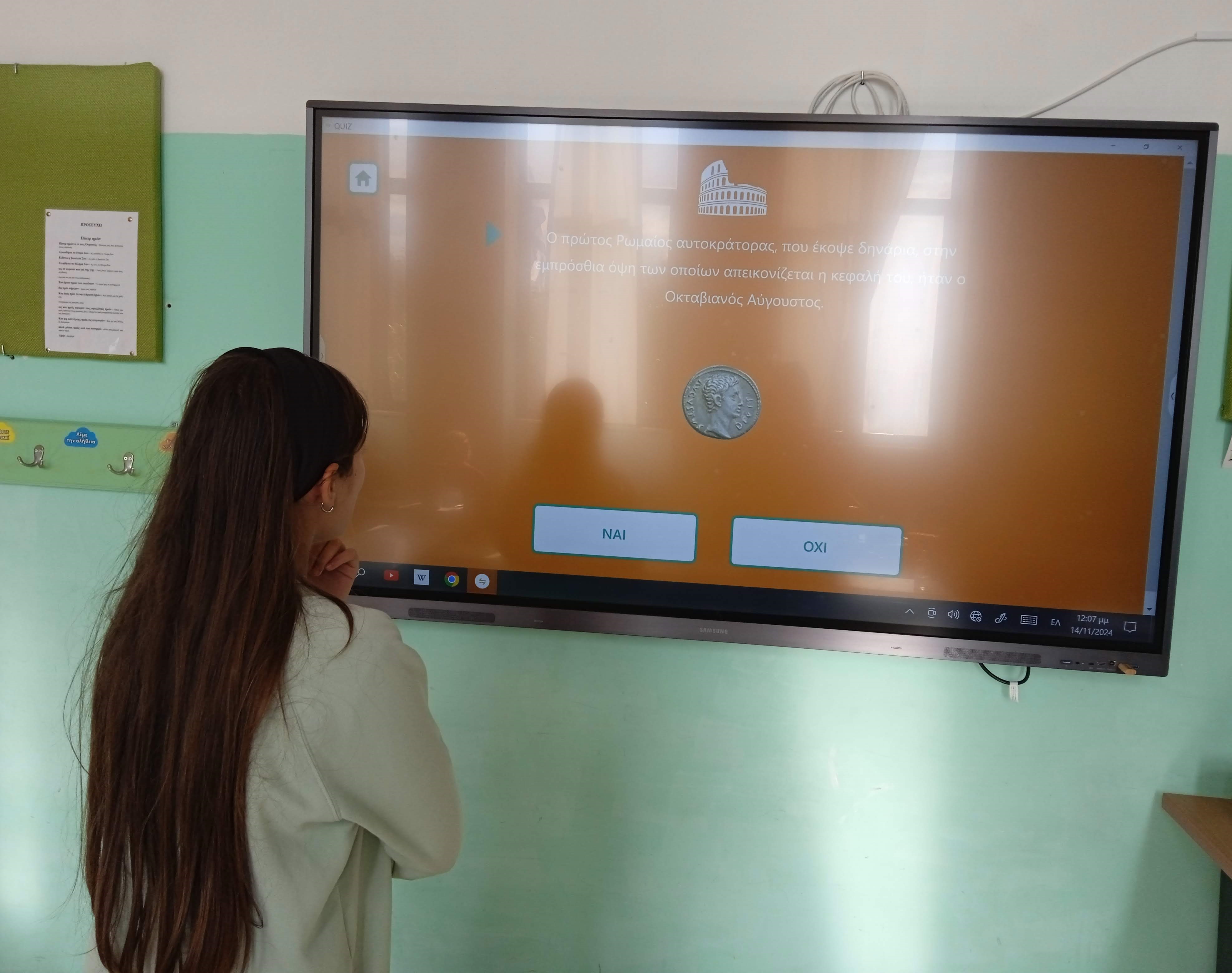Girl in front of an interactive board. On the screen, a quiz from the “Currency and Transactions” programme. Digital educational material