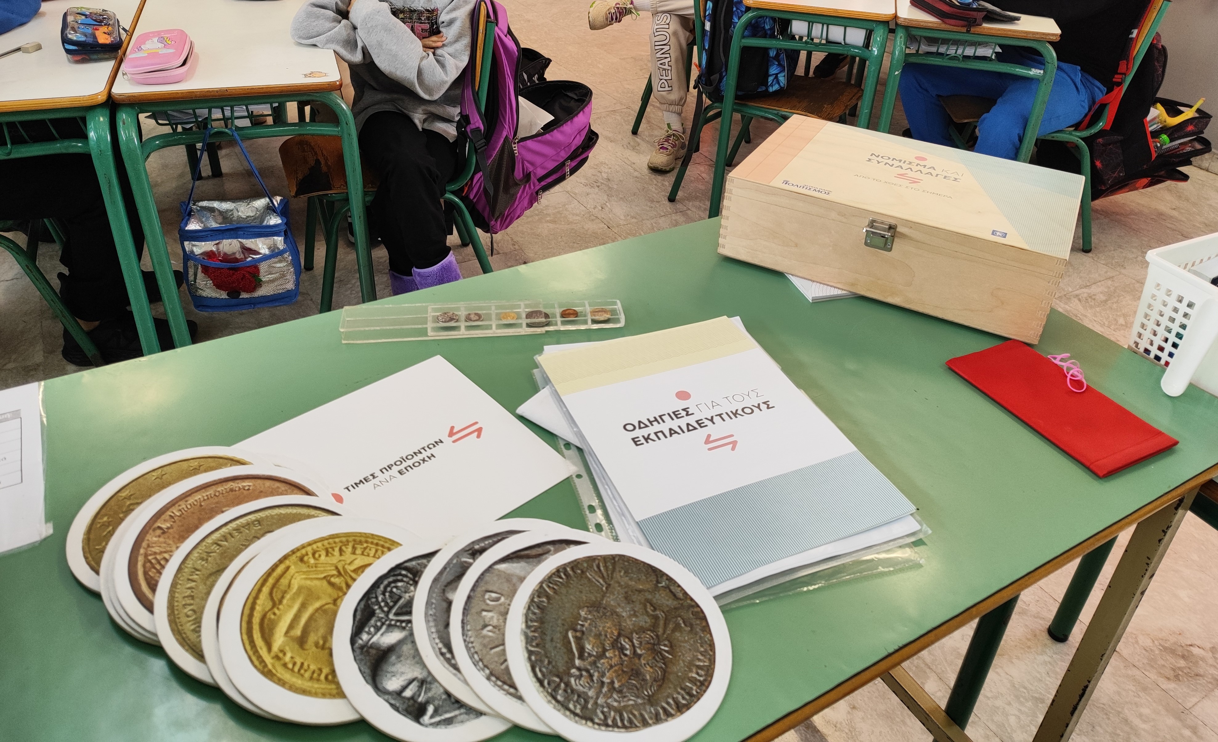 Coin cards, brochures, coin replicas and the “Currency and Transactions” museum kit on a desk. Educational material of the “Currency and Transactions” museum kit
