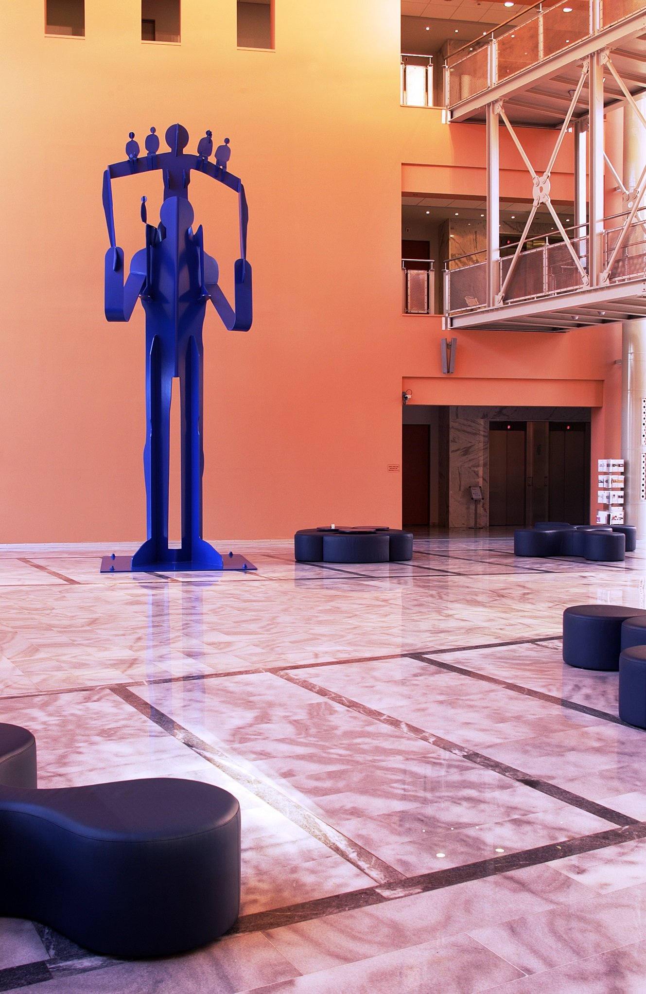 Blue structure of a figure holding on its shoulders a second figure that supports 5 smaller ones. 