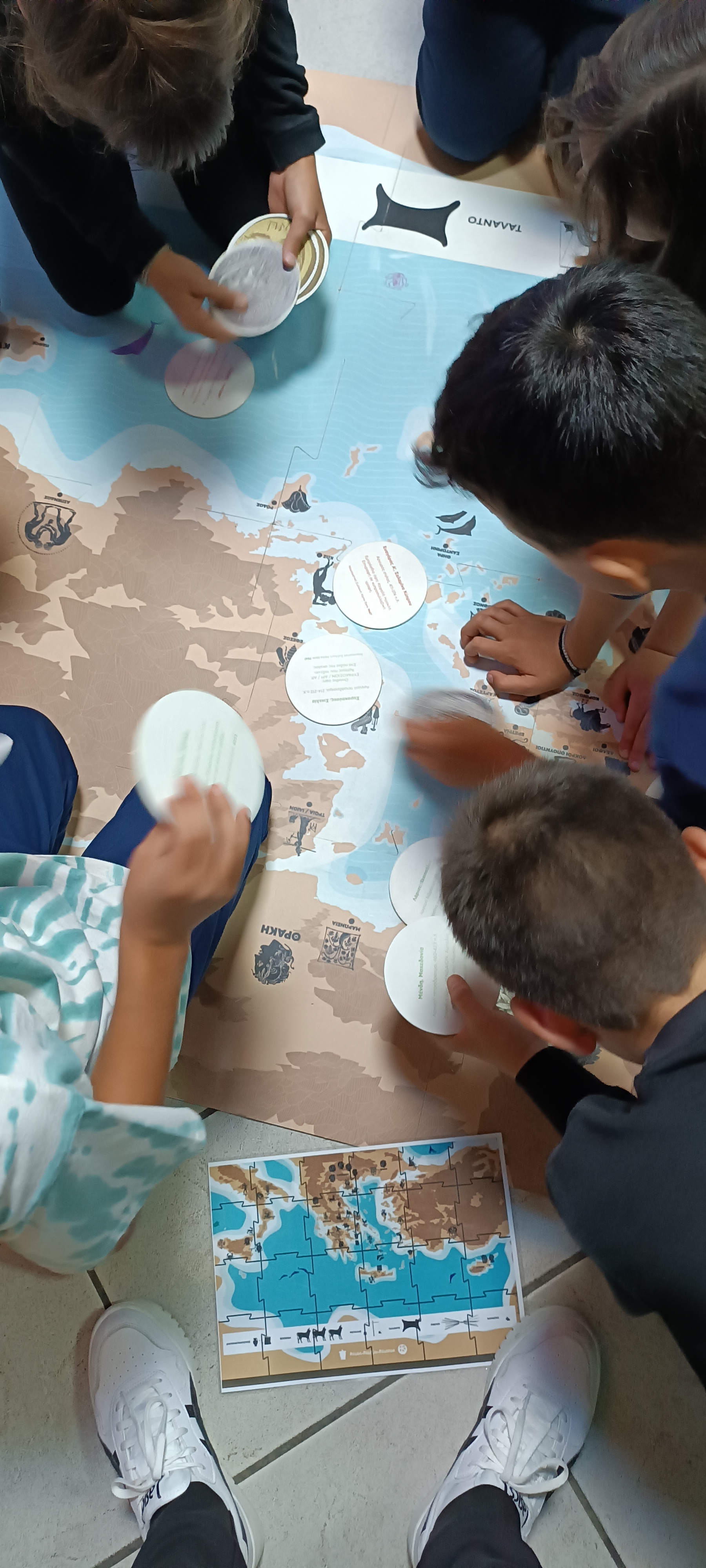 Children placing coin cards on the floor map of the “Nomos-Nomizo-Nomisma” programme. Floor map