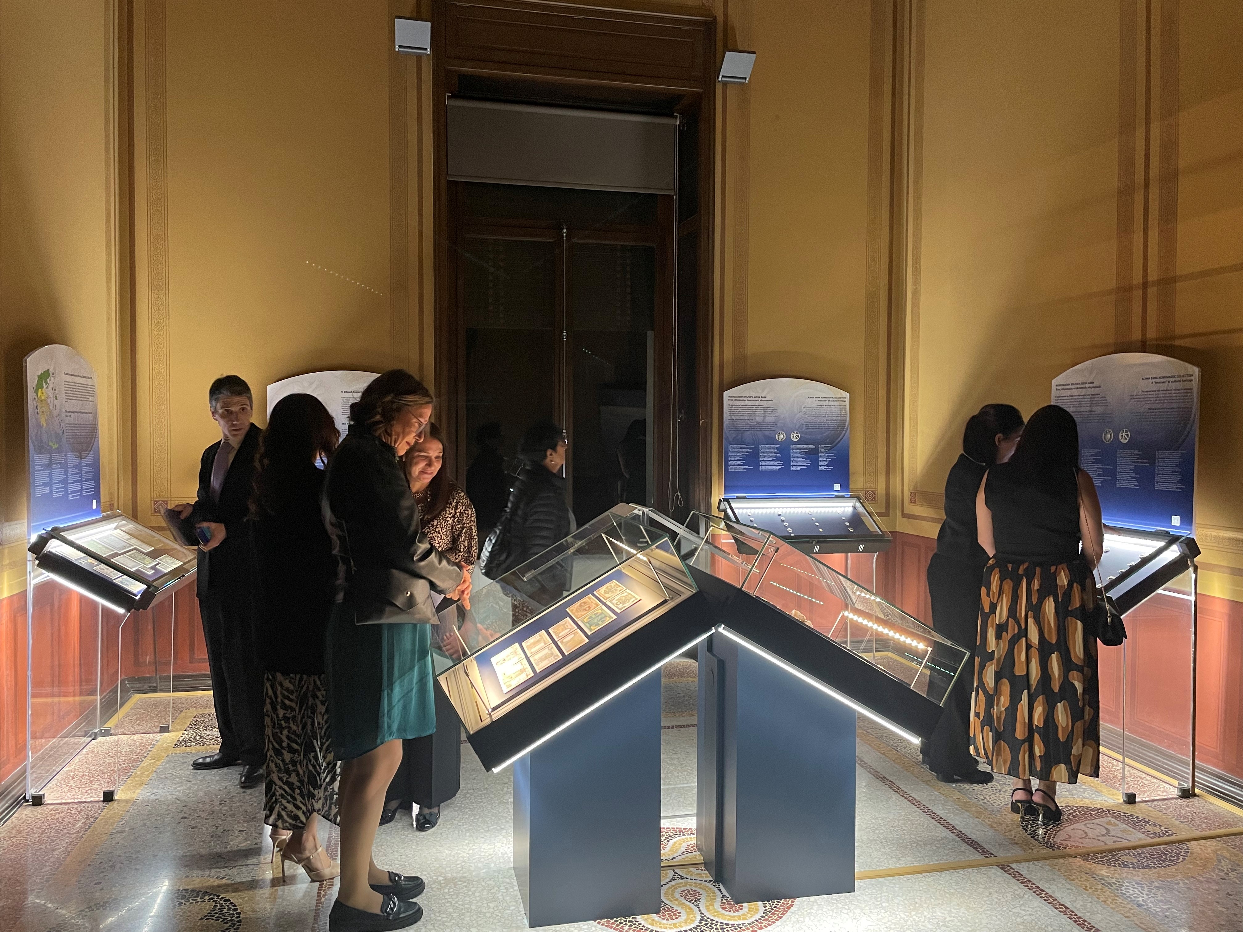 Visitors observing exhibits in the display cases. Highlight from the exhibition opening