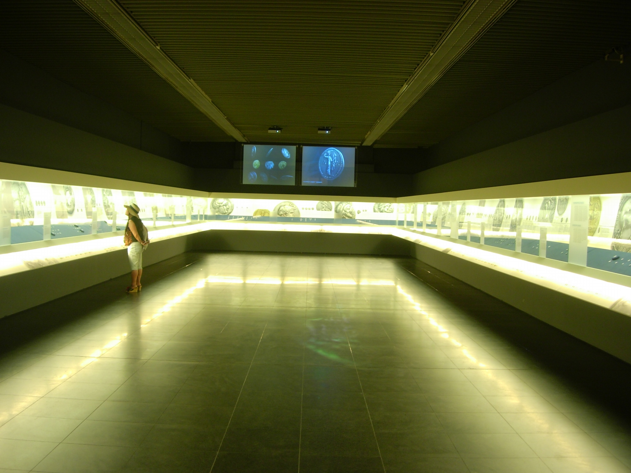 The exhibition area with exhibits in illuminated cases.  Exhibits from “Hellenic Coinage. The Alpha Bank Collection”