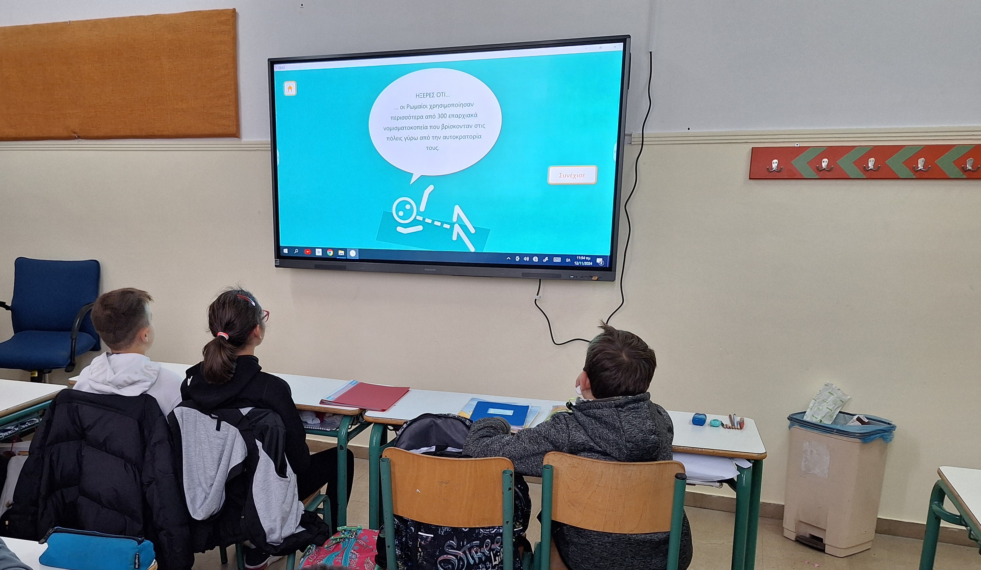 1 girl and 2 boys watching educational material on an interactive board. Digital educational material